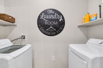 The laundry room has a washer and dryer and a sign on the wall